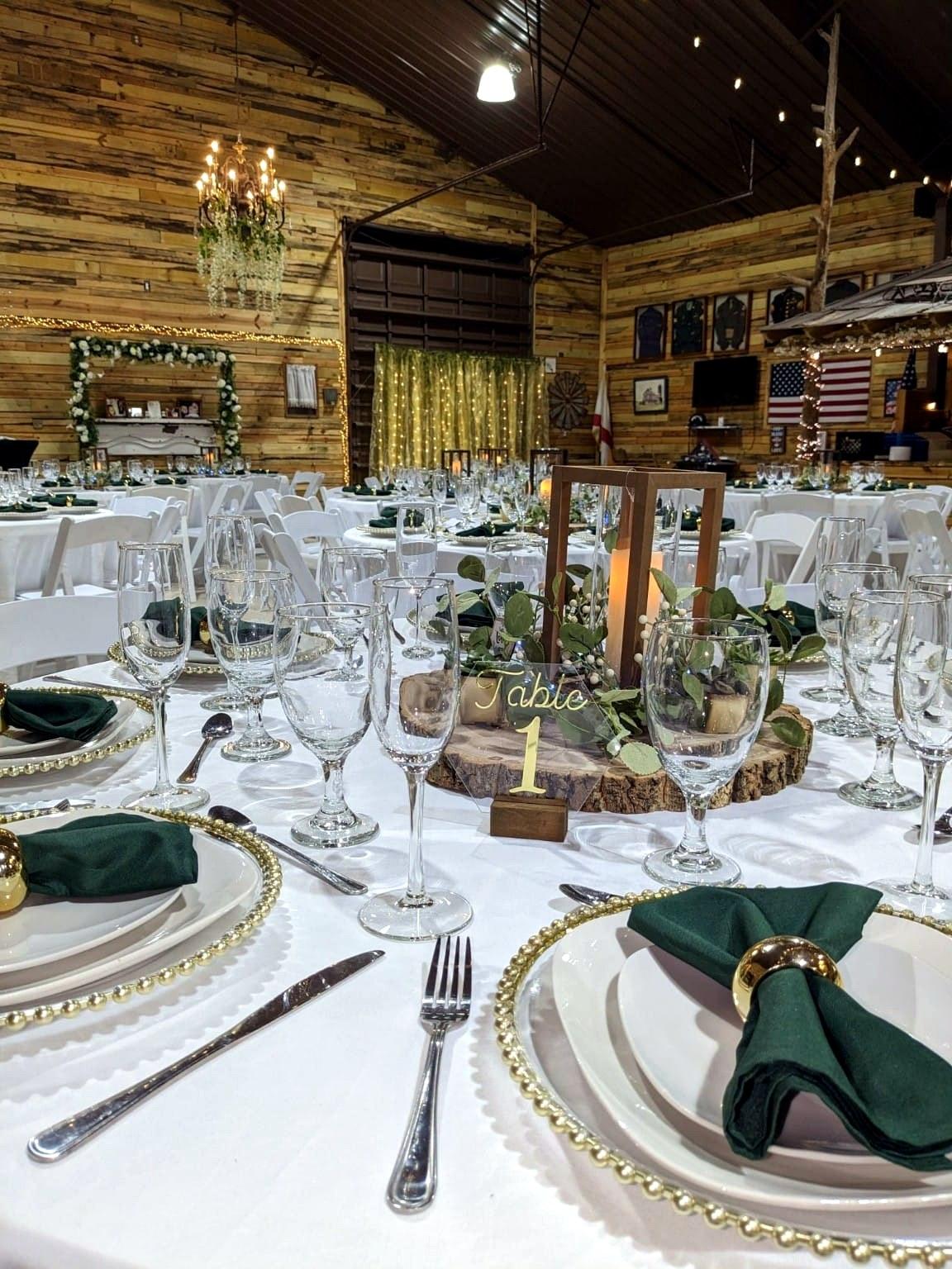 Recepción de boda rústica con servilletas verdes y centros de mesa con linternas