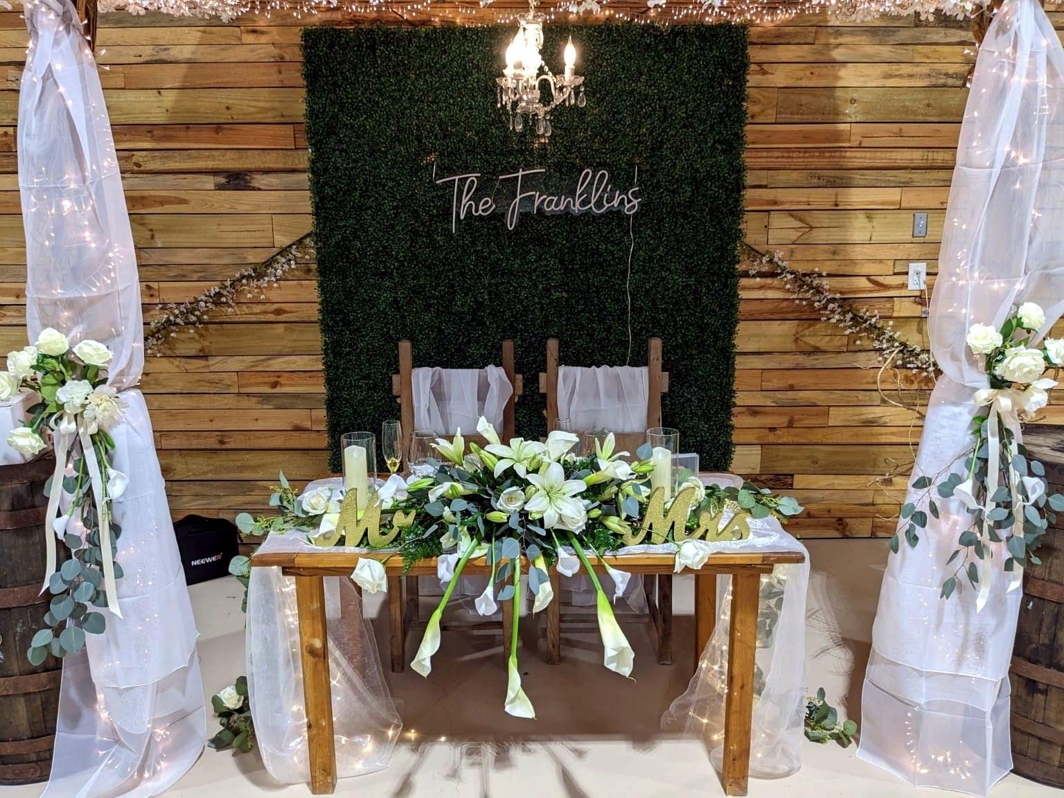 Mesa principal de novios con letrero personalizado y flores blancas